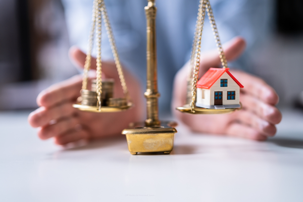 a scale with a house on one side and money on the other